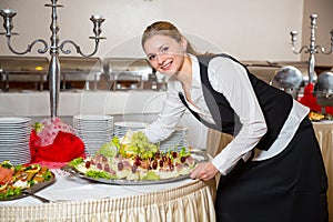 Catering service employee or waitress preparing a buffet
