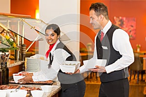 Catering service employees filling buffet in restaurant