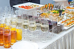 Catering table with alcoholic and non-alcoholic drinks, dishes and snacks food on the event. Service at business meeting, party, w