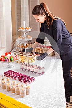 Catering waitress service. Woman at restaurant servicing dessert table