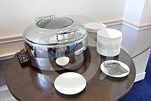 Catering Warming Pot with clear top to see inside food, white plate dishes with utensils on side table