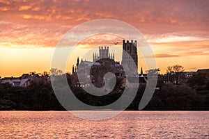 Cathedral of Ely with beautiful sunset colours in the sky infront of a lake