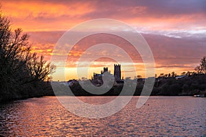 Cathedral of Ely with beautiful sunset colours in the sky infront of a lake