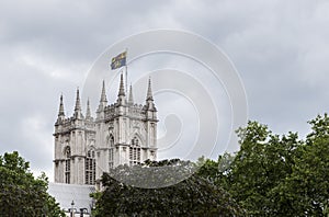 Cathedral tower above green foliage, against a cloudy sky