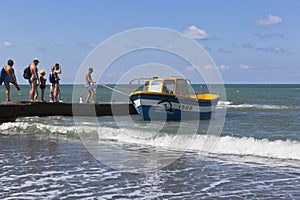 Cather is moored off to a concrete breakwater for boarding of passengers from the beach resort of settlement Adler, Sochi