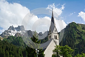 Catholic church in Arabba village with cable car Porta Vescovo on the background, Italy