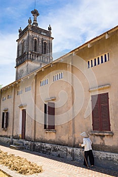 Catholic Church in Duong Lam ancient village, Son Tay district, Hanoi, Vietnam. Vietnamese old woman with stick walking to the chu