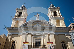Catholic church with two bell towers and statue of the Virgin Mary against blue sky