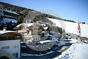 Catholic church and village in the Italian dolomites in wintertime with snow.