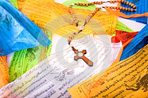 Catholic cross on colorful Tibetan Sanskrit banners with religious prayers