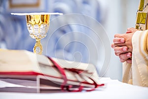 Catholic mass - the hands of the priest and golden chalice with wine