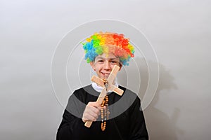 Catholic pastor in a clown wig with a cross and rosary. The concept of mockery of sectarianism and fanaticism photo