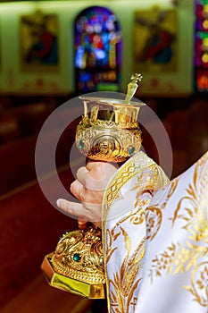 catholic priest with chalice cup during consecration ceremony