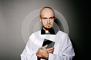 Catholic priest in white surplice holding bible photo