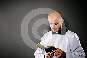 Catholic priest in white surplice reading bible photo