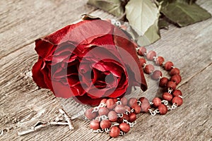 Catholic rosary and red rose