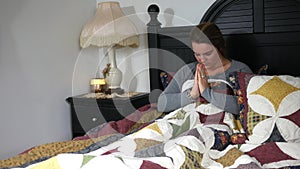 A Catholic woman praying in bed