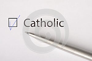 Catolic - checkbox with a tick on white paper with metal pen. Checklist concept photo
