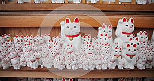 Cats, Gotokuji and temple of manekineko in Japan for luck, success and gratitude outdoor on wooden furniture. Sculpture