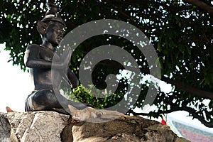 Cats have a rest near the sculpture of a meditating person in the territory of a Buddhist monastery