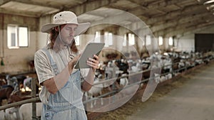 Cattleman using digital tablet for work at goat farm