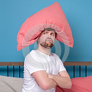 Cauacsian young man with pillow on head lying in bed and screaming being alone stressed because of quarantine