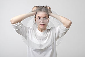 Cauasian woman in panic in studio. halding her head. She is holding her head with hands. photo