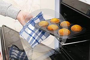 Caucasain woman holding tray with freshly made cupcakes or maffins at the kitchen photo