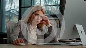 Caucasian adult 40s businesswoman typing computer in office tired sleepy sitting at office desk exhausted bored middle