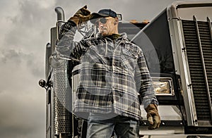 Caucasian American Trucker in Front of His Black Semi Truck Tractor