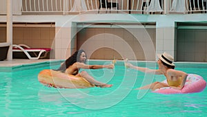 Caucasian Arabian women model cheerful beautiful diverse tanned girl friends relax in pool of luxury spa hotel resort