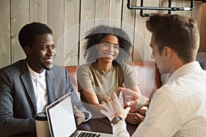 Caucasian architect consulting black clients out in coffee shop