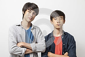 Caucasian and Asian teen boys wear shirt and stand on white background.