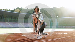 Caucasian Athlete ready to start. Young female runner with personal trainer preparing for blasting off in mist on sports