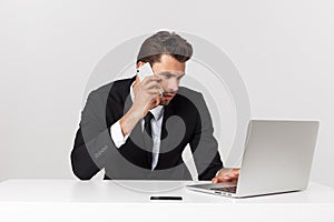 Caucasian attractive businessman worried and tired talking on mobile phone sitting at office desk working in stress