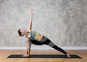 Caucasian attractive girl in yoga pose Bikram triangle standing against texturized wall