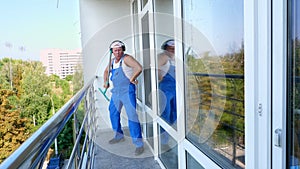 Caucasian attractive man, cleaning service worker, in blue overalls with headphones, having fun, dancing, playing on