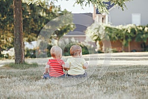 Caucasian babies sitting together in field meadow outside