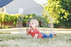 Caucasian baby boy in red t-shirt and pants in grass in field meadow outside