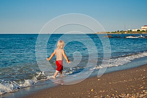 Caucasian baby boy walk on the beach