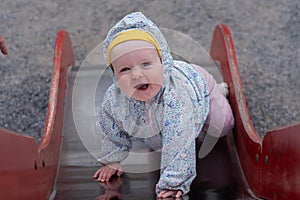 Caucasian baby girl climbing up the slide laughing