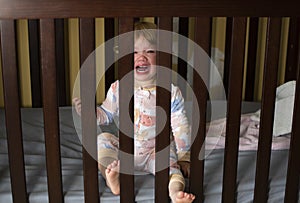 Caucasian baby girl crying in the crib. Sad Sick child