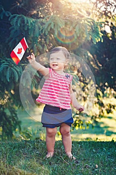 Caucasian baby girl holding Canadian flag with red maple leaf