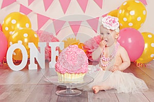 Caucasian baby girl in tutu tulle skirt celebrating her first birthday. Cake smash concept