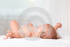 A caucasian baby is lying in bed. Side view, close-up. Copy space. Mother`s Day concept