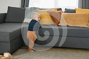 Caucasian baby newborn infant making first steps. Cute toddler kid child son boy learning walking creeping on living