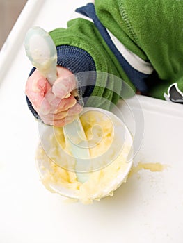 Caucasian baby's hand using spoon to eat