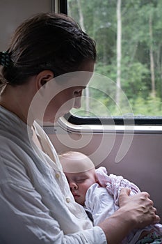 Caucasian baby sleeping traveling by train on mother lap