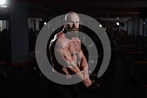 Caucasian bald man posing in the gym.