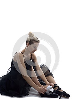 Caucasian Ballet Dancer in Body Suit Preparing for Dance While Sitting on White Floor Against White Background